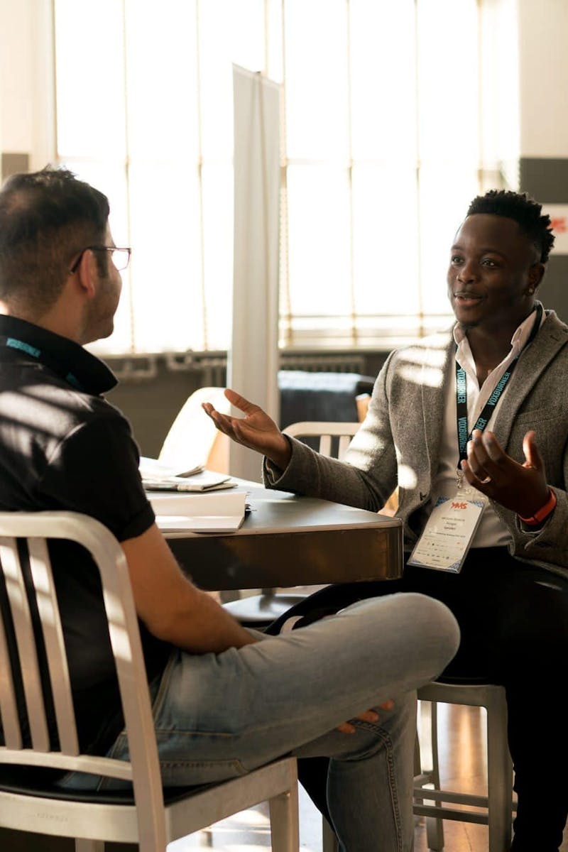 Two men having a casual discussion in a bright indoor setting, highlighting mentorship.